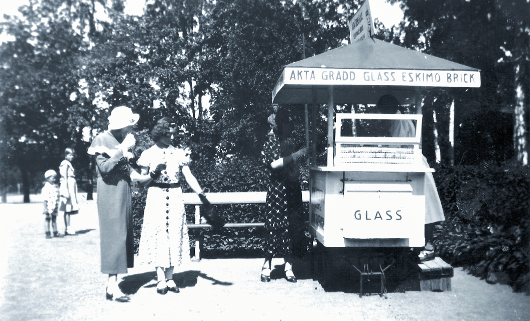 Kaksi kesämekkoon pukeutunutta naista jäätelökioskilla vanhassa valokuvassa