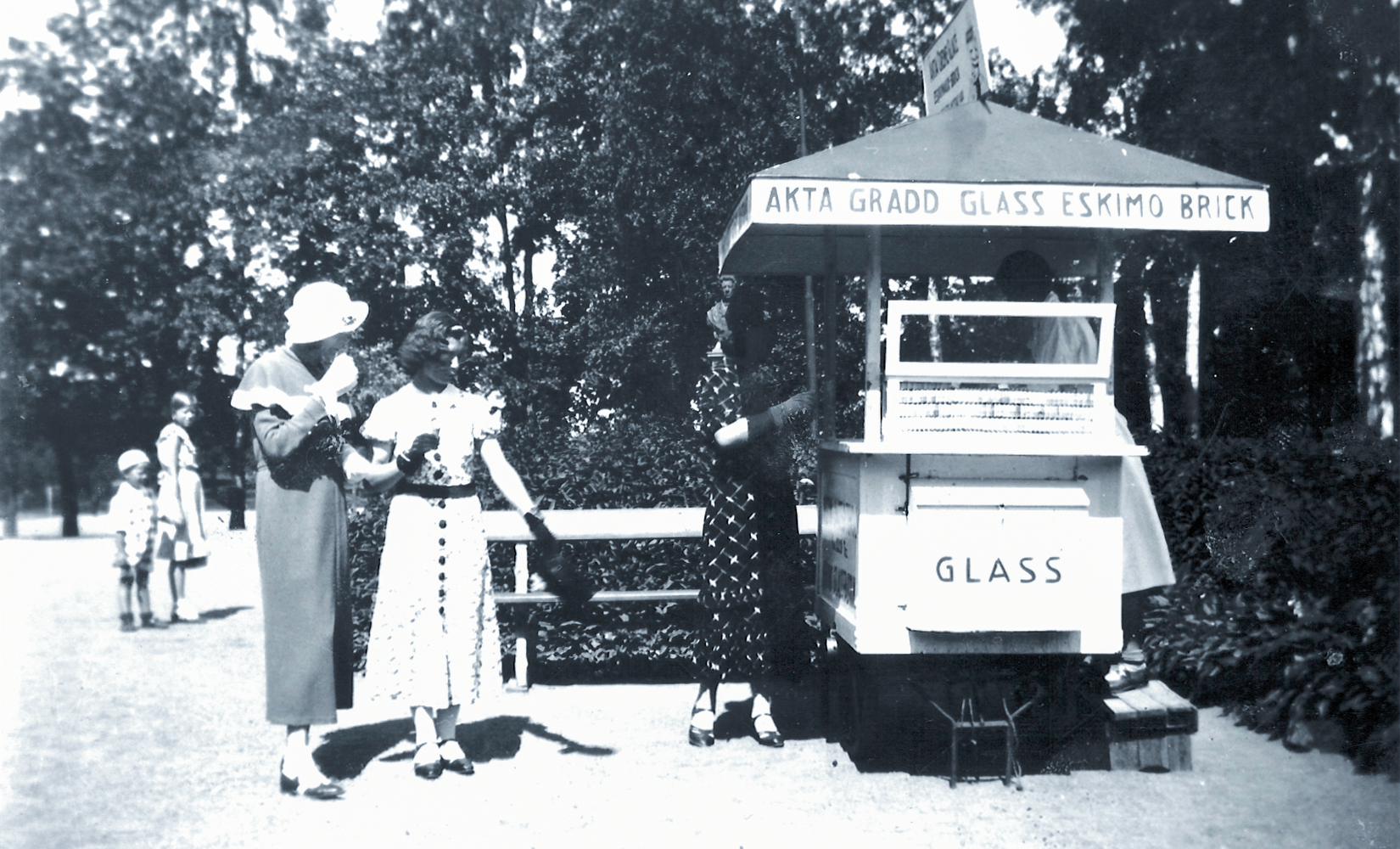 Two women in early 20th century dresses having ice cream in black and white picture